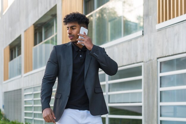 Retrato horizontal de un joven empresario árabe distraído hablando por teléfono en la calle