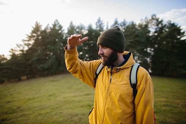 Retrato horizontal de un joven excursionista haciendo senderismo en las montañas con mochila de viaje Hombre viajero con barba trekking y montañismo Concepto de estilo de vida saludable para personas de viaje