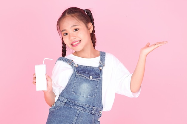 Retrato horizontal de una linda y hermosa niña asiática sosteniendo una caja de leche aislada en el fondo