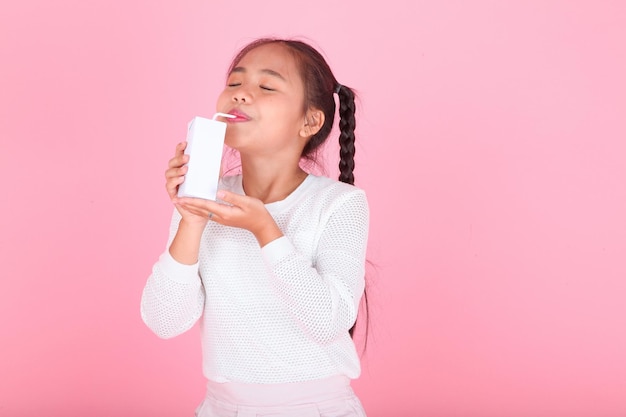 Retrato horizontal de una linda y hermosa niña asiática sosteniendo una caja de leche aislada en el fondo