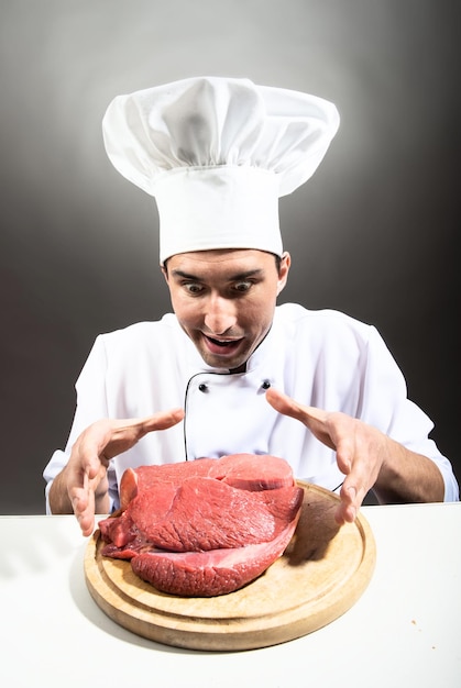 Retrato humorístico de um homem com chapéu de chef com um pedaço de carne