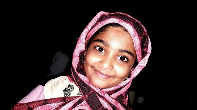 Foto retrato inclinado de menina com lenço de cabeça à noite