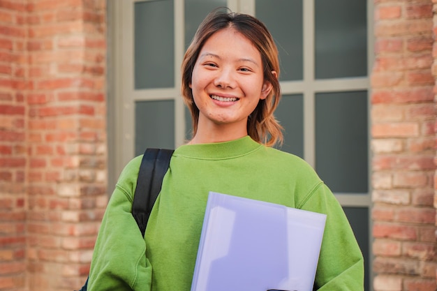 Retrato individual de una joven estudiante de secundaria asiática sonriendo y mirando a la cámara china
