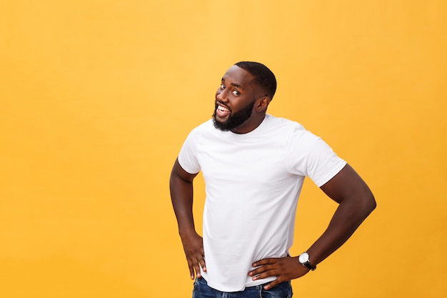 Retrato del individuo africano joven hermoso que sonríe en la camiseta blanca en fondo amarillo