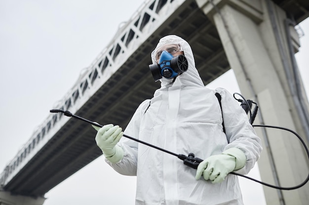 Retrato industrial de baixo ângulo de um homem vestindo roupas anti-perigos sob o espaço da cópia da ponte