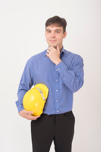 Un retrato de un ingeniero con casco de seguridad amarillo está en el estudio de fondo blanco