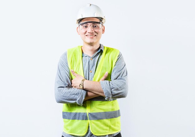 Retrato de un ingeniero guapo y sonriente con brazos cruzados aislado Retrato de un joven ingeniero alegre con casco y chaleco aislado