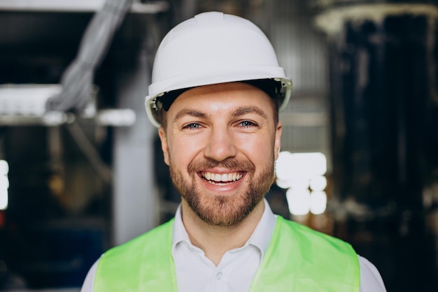 Retrato de ingeniero masculino sonriendo con casco en una fábrica