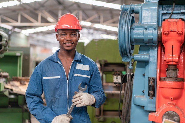 Retrato de ingeniero trabajador negro vistiendo uniforme de seguridad con soporte de herramienta de llave de sujeción en fábrica