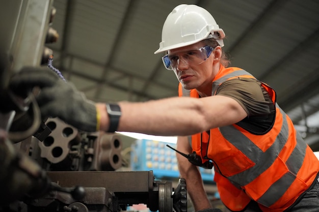 Retrato de ingeniero/trabajador profesional de la industria pesada con uniforme de seguridad, gafas y sombrero duro. En el fondo gran fábrica industrial desenfocada