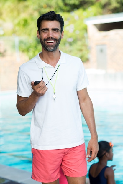 Retrato de instructor masculino de pie junto a la piscina