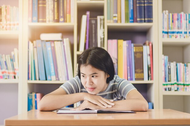 Retrato de inteligente estudiante asiático leyendo e investigando en la biblioteca de la universidad