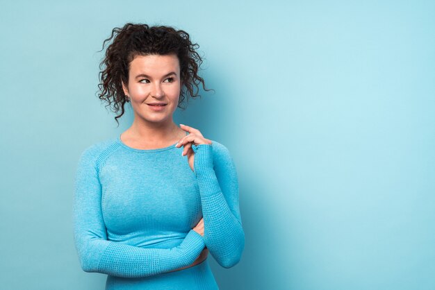 Foto retrato interior de mujer rizada caucásica adulta. ella lleva un traje deportivo azul casual sexy. mujer mirando a otro lado. concepto de deportista