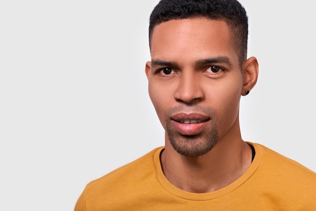 Retrato interior de primer plano de un apuesto hombre afroamericano posando para un anuncio aislado en una pared blanca con espacio en blanco para su texto publicitario Emoción de la gente y concepto de estilo de vida