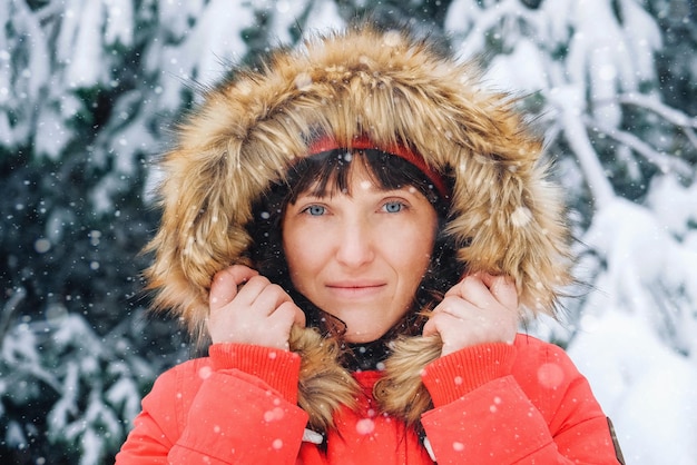 Retrato invernal de una mujer vestida de rojo sobre un fondo de árboles cubiertos de nieve