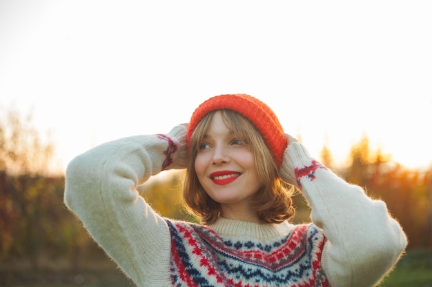 Retrato de invierno brillante de una hermosa mujer joven en un sombrero rojo de punto contra el fondo de los árboles de Navidad Eco Navidad vacaciones de invierno Año Nuevo