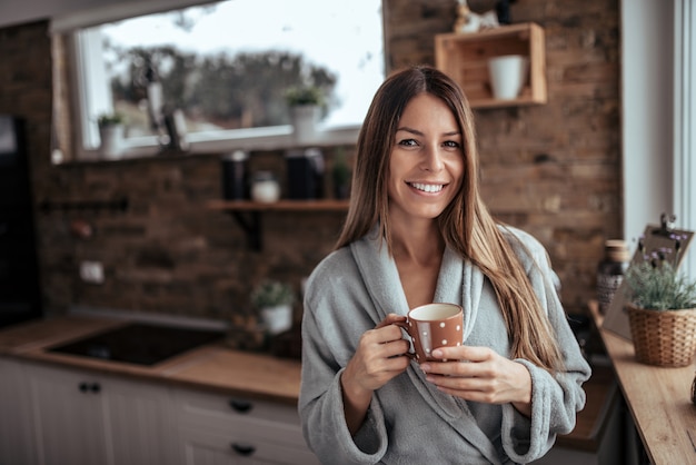 Retrato del invierno de un café de consumición de la mañana de la mujer morena.