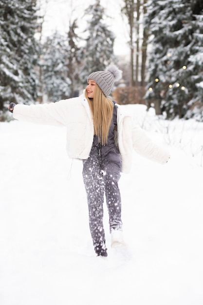 Retrato de invierno de una joven feliz jugando con nieve en el bosque