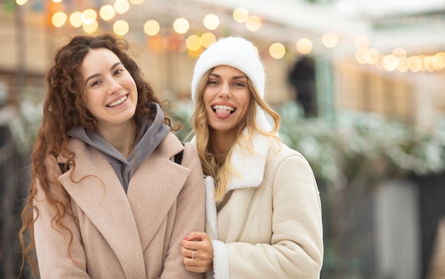 Retrato de invierno de moda sonriendo amigas. Mujer feliz divirtiéndose al aire libre.