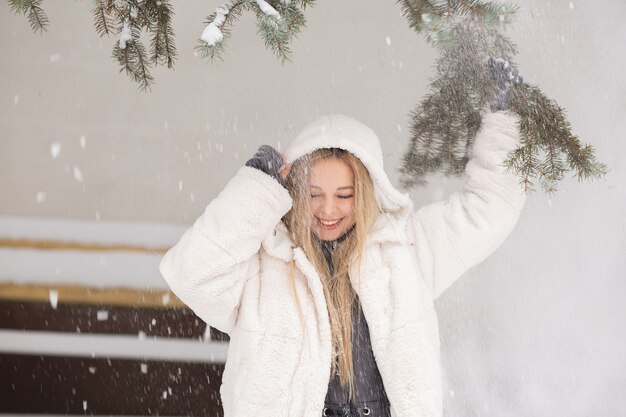 Retrato de invierno de una mujer joven emocional jugando con nieve en el bosque. Espacio vacio