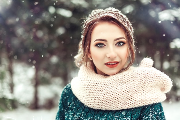 Retrato de invierno de niña bonita en el parque nevado