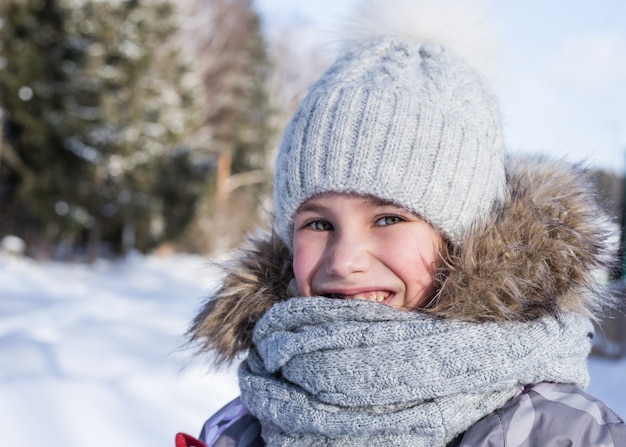 Retrato de invierno de niña feliz con bufanda y gorro de punto