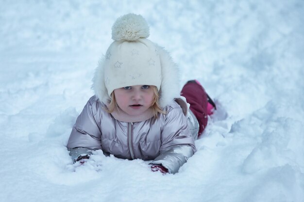 Retrato de invierno niña feliz en un parque público cubierto de nieve con ropa de abrigo