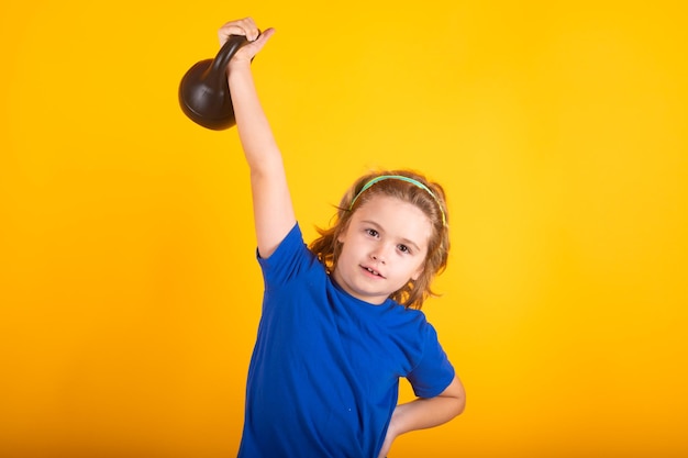 Retrato isolado de estúdio infantil esportivo em fundo amarelo Exercícios esportivos infantis Conceito de vida e esporte infantil saudável Retrato de menino malhando com halteres