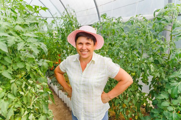 retrato de un jardinero caucásico sonriente con los brazos en las caderas y el sombrero mirando a la cámara una mujer mayor feliz posando en el espacio de copia del jardín