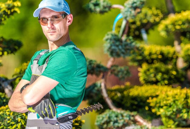 Retrato de un jardinero de pie junto a las plantas