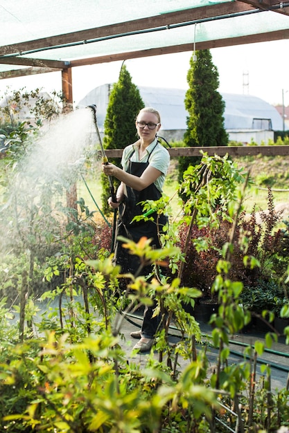 Retrato de jardinero regar las hierbas en la tienda de jardinería, día soleado