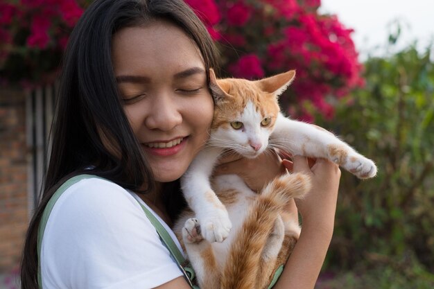 Retrato jovem asiática com um gato ao ar livre lindo fundo de flores