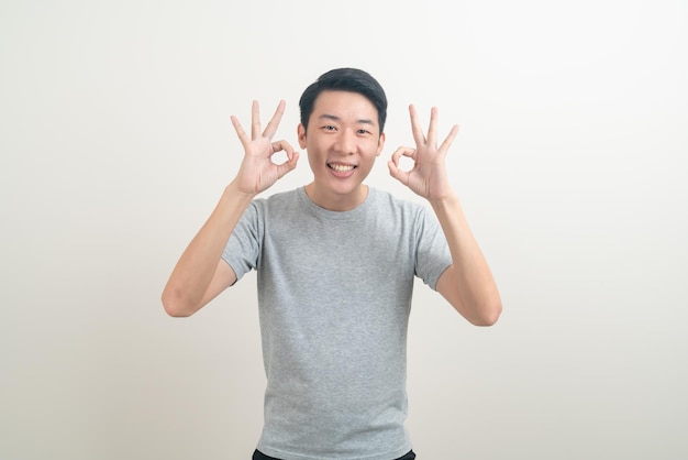 retrato jovem asiático com polegar para cima ou sinal de mão ok no fundo branco