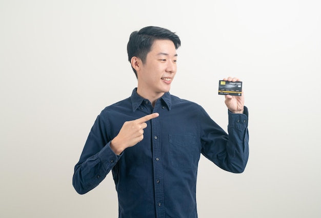 retrato jovem asiático segurando um cartão de crédito no fundo branco