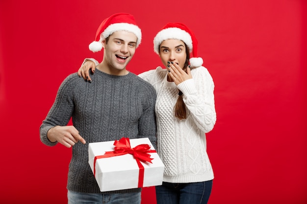 Retrato jovem casal em camisola de natal apontando gesto de dedo para presentes.