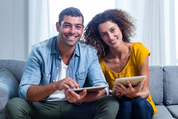 Foto retrato jovem casal sentado no sofá e usando tablet digital