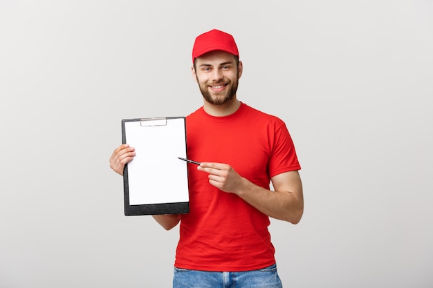 Retrato jovem caucasiano bonito entregador ou correio mostrando um formulário de documento de confirmação para assinar.