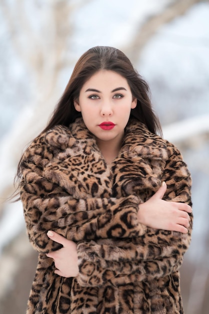 Retrato jovem com cabelo comprido vestido com casaco de pele falsa com padrão de leopardo olhando para a câmera