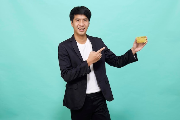 Retrato Jovem empresário bonito de terno segurando cartão de crédito amarelo isolado em um estúdio azul