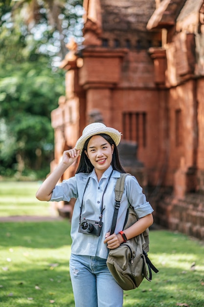 Retrato jovem mochileiro feminino usando chapéu, viajando em local antigo, ela usa a câmera para tirar fotos com felicidade, copie o espaço