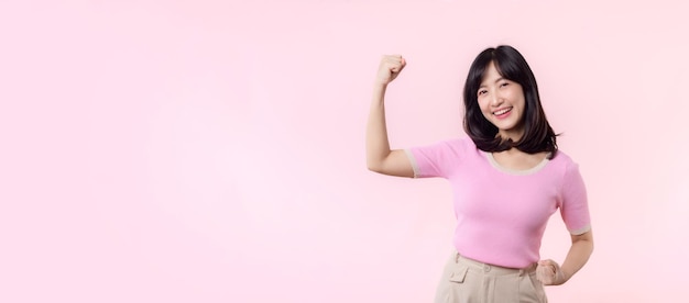 Retrato jovem mulher asiática orgulhosa e confiante mostrando forte força muscular braços flexionados posando sente sobre sua conquista de sucesso mulheres empoderamento igualdade força saudável e conceito de coragem