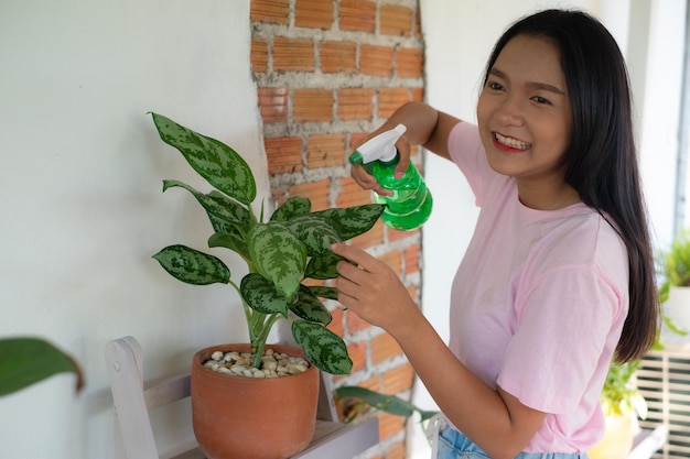 Retrato jovem regando plantas verdes em casa menina asiática