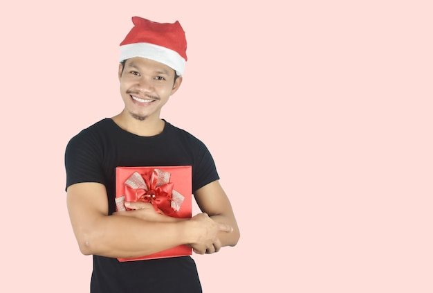 Retrato de joven abrazando caja de regalo roja sobre fondo rojo.