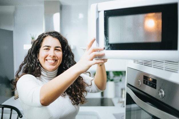 Foto retrato de una joven abriendo el microondas