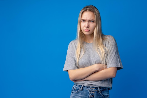 Retrato de joven adolescente infeliz insatisfecho sobre fondo azul.