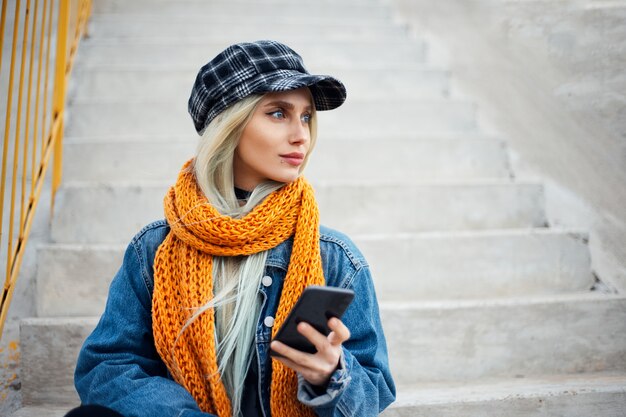 Retrato de joven adolescente rubia con smartphone en mano