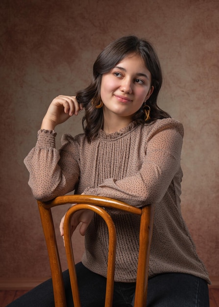 Foto retrato de una joven adolescente sentada en una silla y mirando hacia un lado.