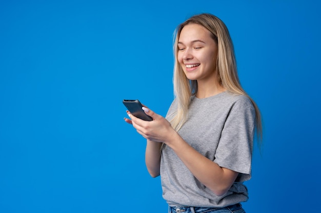 Retrato de una joven adolescente con smartphone sobre fondo azul.