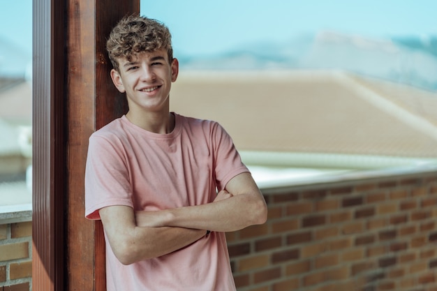 Retrato de un joven adolescente sonriente con cabello castaño en una terraza