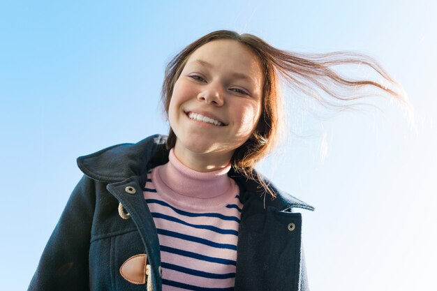 Retrato de joven adolescente sonriente, cielo azul de fondo